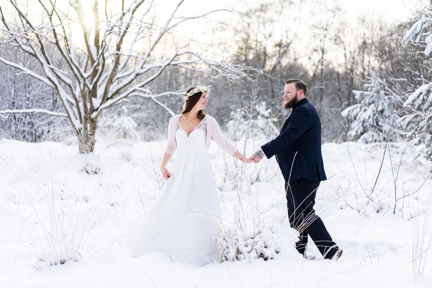 Braut zieht ihren Bräutigam hinterher gemeinsamer Spaziergang im Schnee Hochzeitsfotos Bremen
